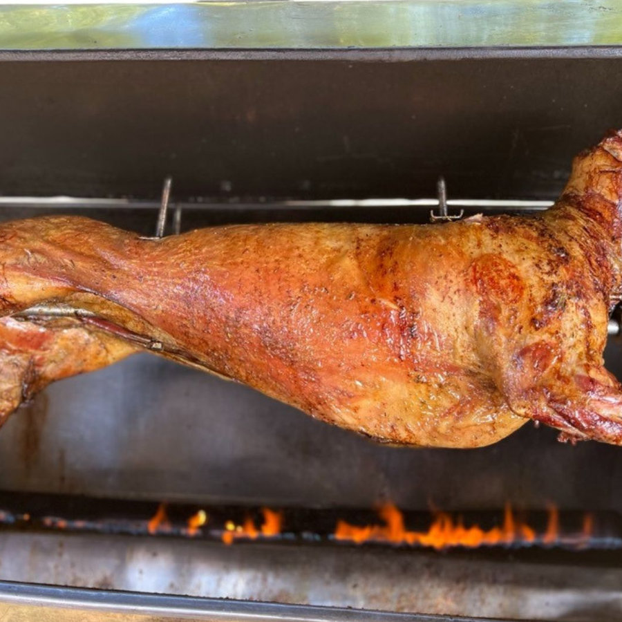 Spit roast lamb cooking over fire